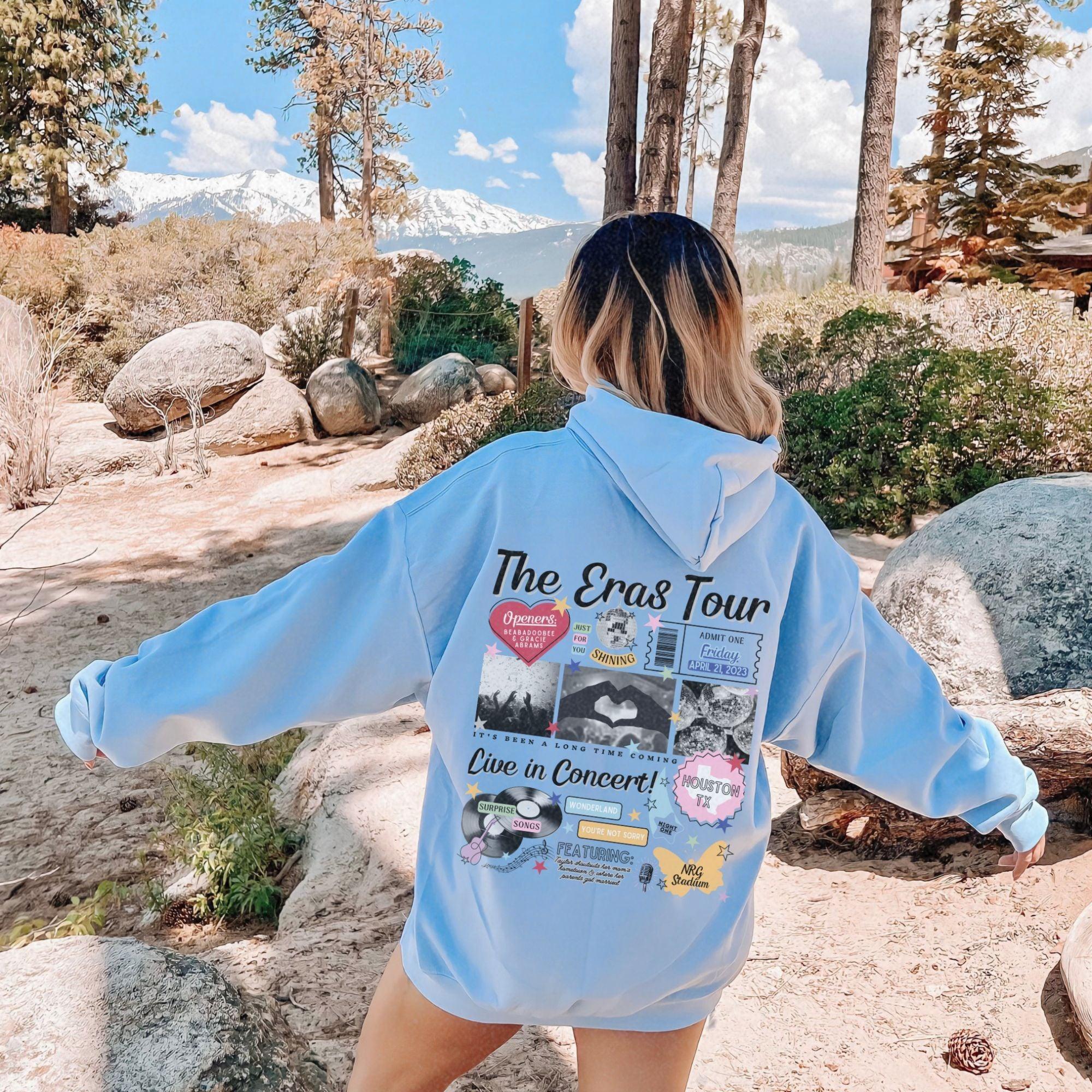 a woman in a blue hoodie is standing on a rock