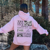 a woman in a pink hoodie is standing in the woods