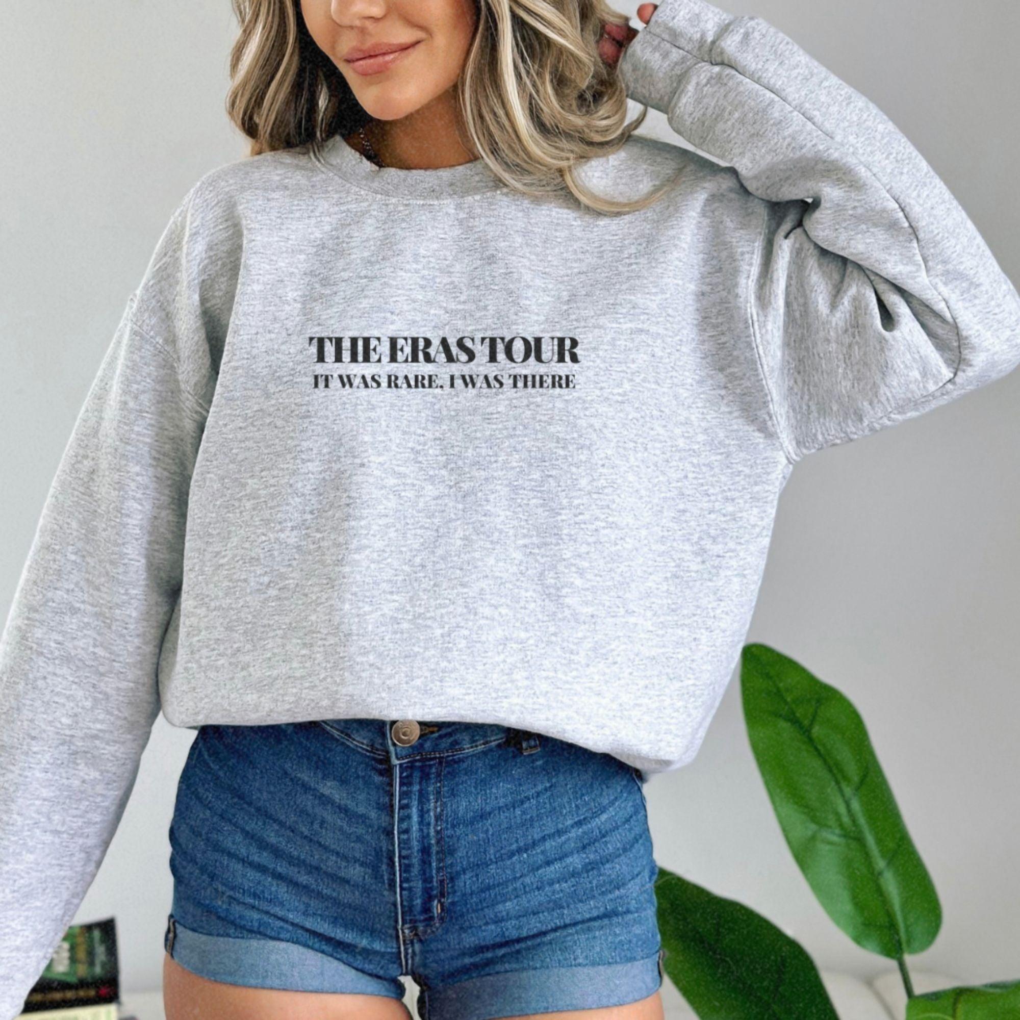 a woman wearing a grey sweatshirt and denim shorts