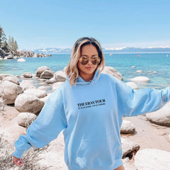 a woman in a blue sweatshirt standing on a beach