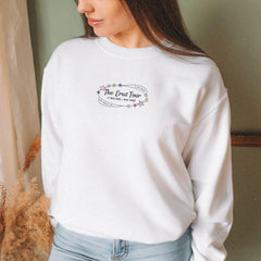 a woman standing next to a window wearing a white sweatshirt