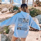 a woman in a blue hoodie is walking in the woods