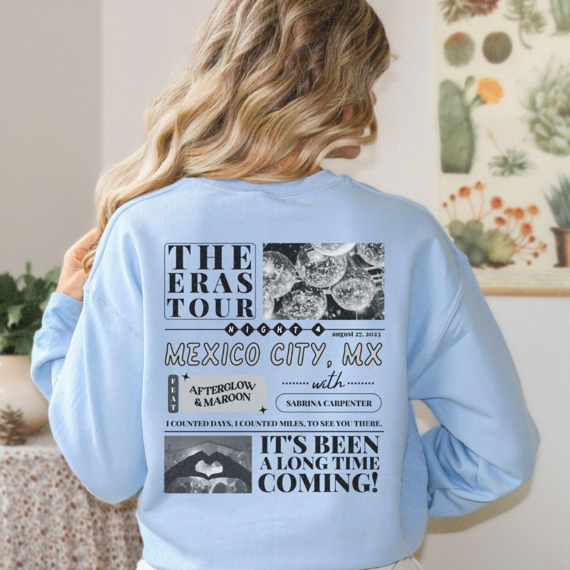 a woman wearing a light blue sweatshirt with the words the eras tour mexico city,