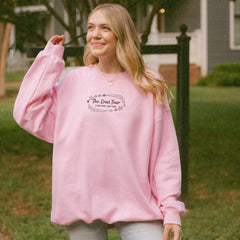 a woman in a pink sweatshirt is standing in front of a house