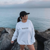 a woman standing on a rock next to the ocean