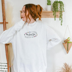 a woman wearing a white sweatshirt with the words the great tour on it