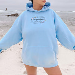 a woman standing on a beach wearing a blue hoodie