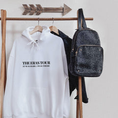 a white sweatshirt hanging on a rack next to a backpack