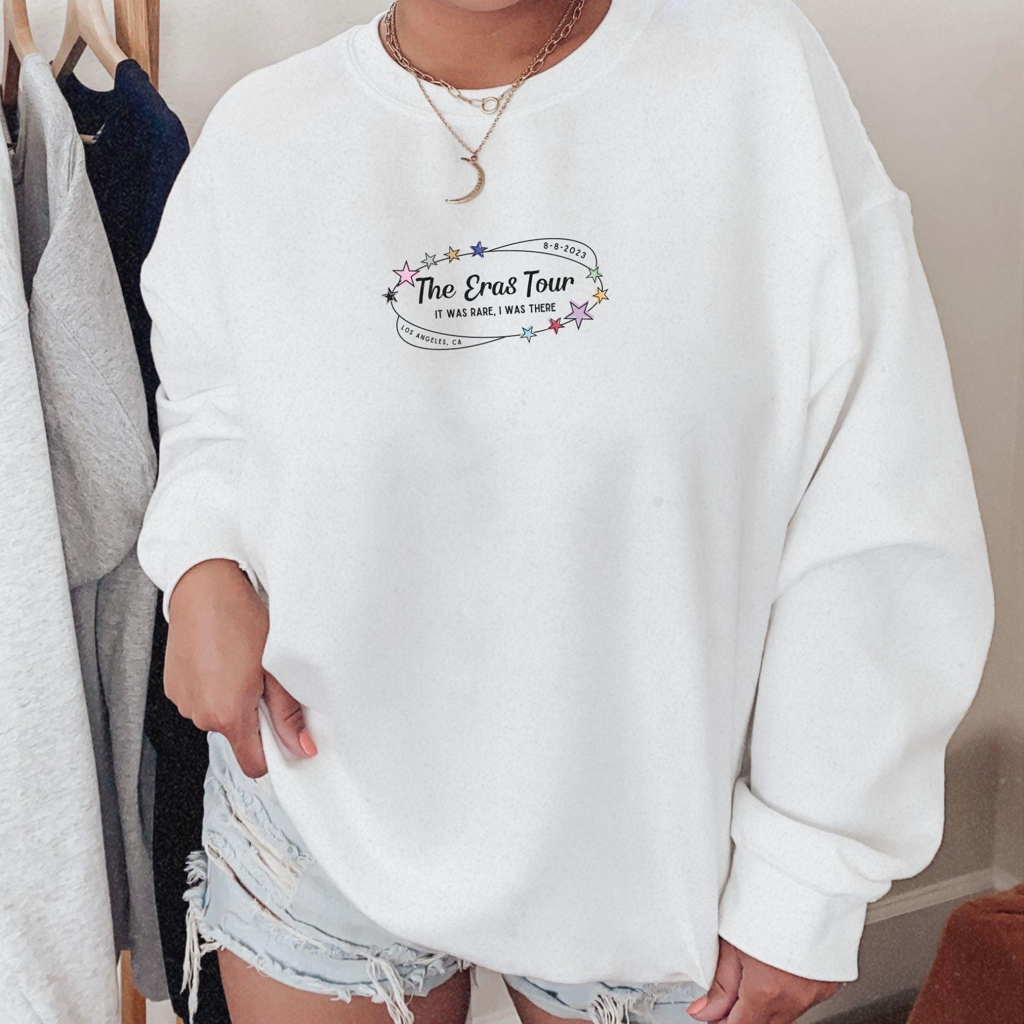 a woman wearing a white sweatshirt and ripped shorts