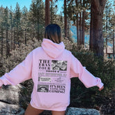 a woman in a pink hoodie standing on a rock
