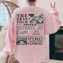 a woman wearing a pink sweatshirt with the words detroit on it