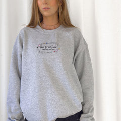 a woman wearing a grey sweatshirt with the words the great tour on it