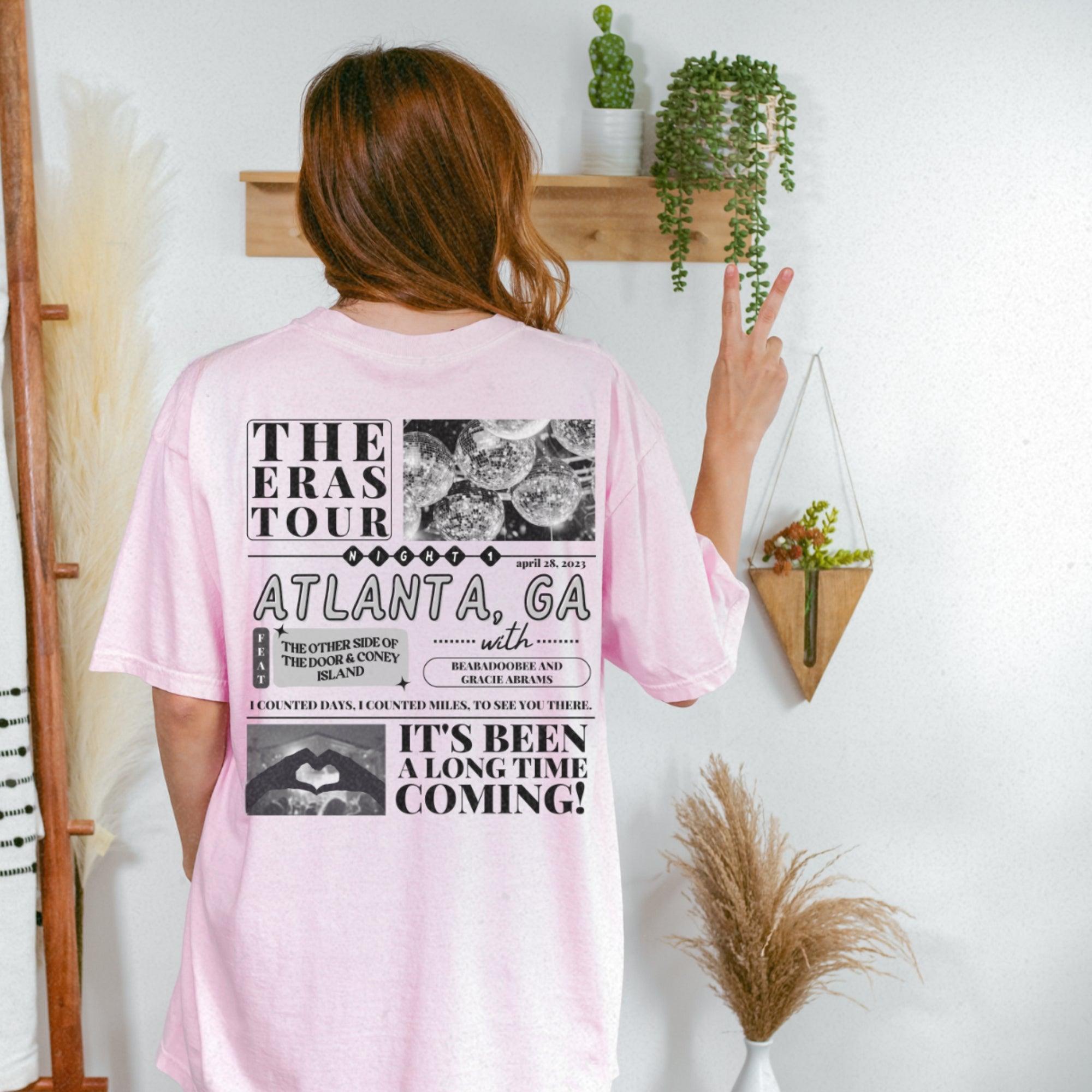 a woman wearing a pink tshirt standing in front of a wall