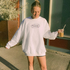 a woman in a white sweatshirt and black shorts holding a drink