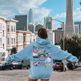 a woman in a blue hoodie standing on a sidewalk