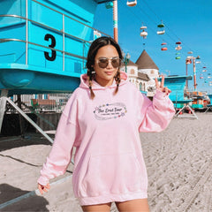 a woman in a pink hoodie on the beach
