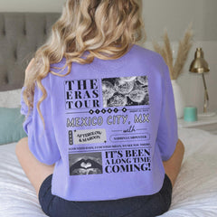 a woman sitting on top of a bed wearing a purple shirt