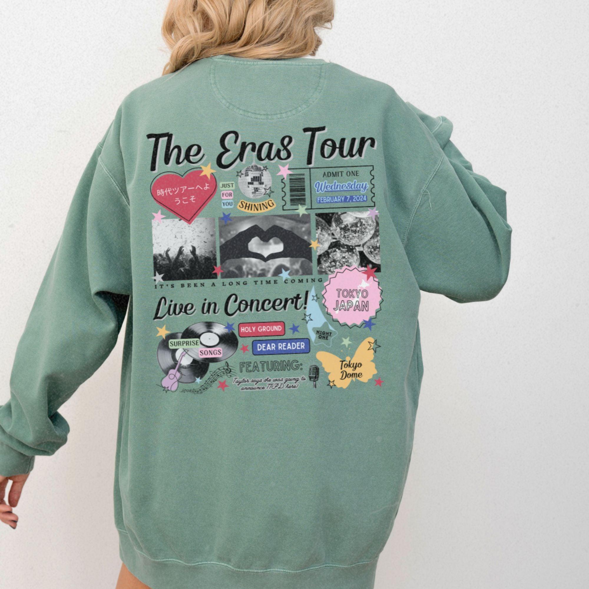 a woman wearing a green sweatshirt with the words the eras tour on it