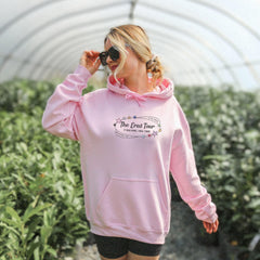 a woman in a pink hoodie walks through a greenhouse