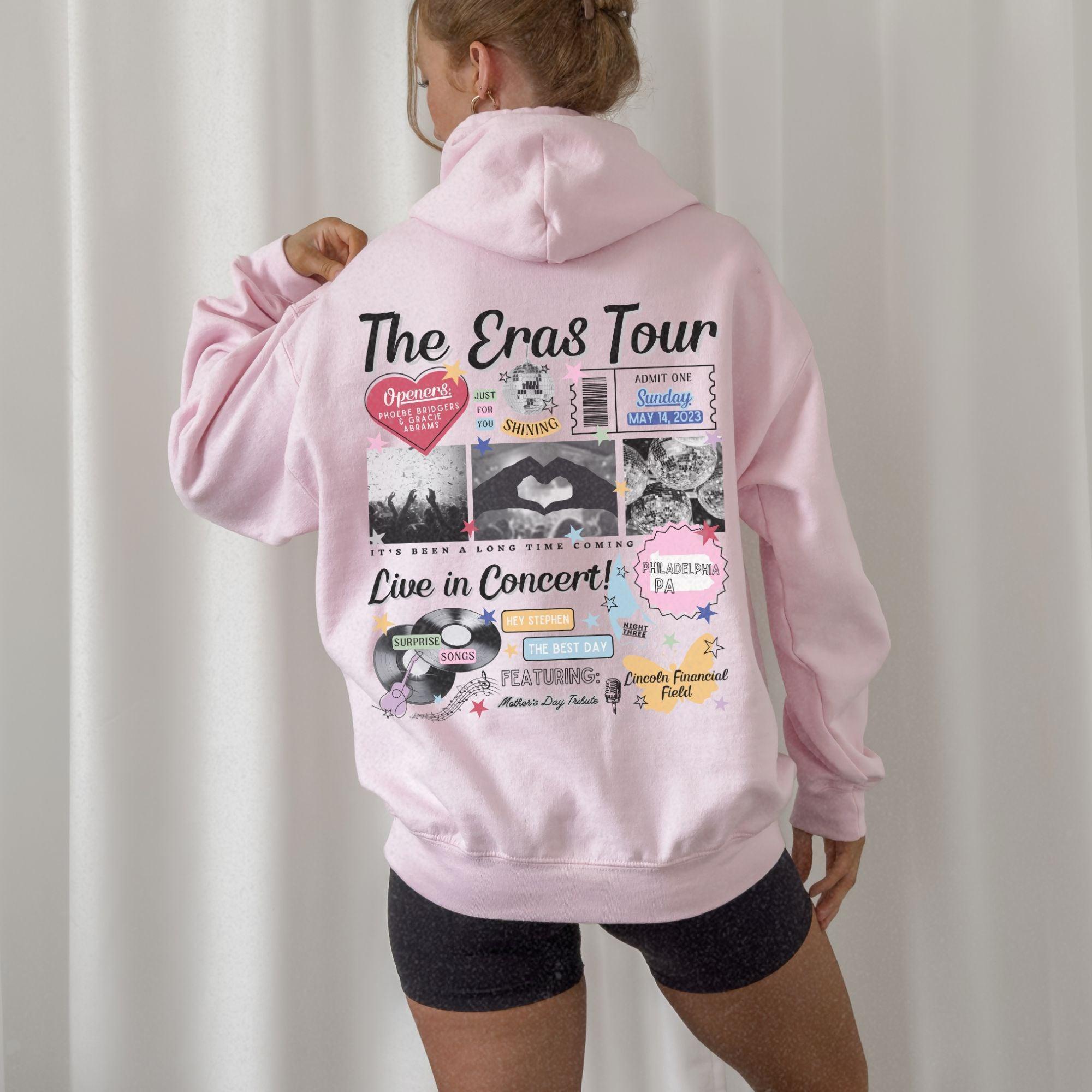 a woman wearing a pink hoodie with the words the eros tour on it