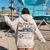 a woman in a white hoodie walking towards a blue lifeguard tower