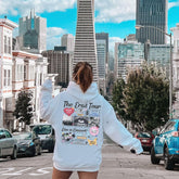 a woman in a white hoodie walking down a street