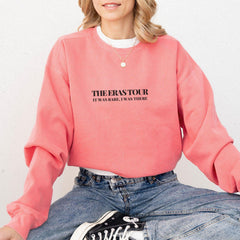 a woman sitting on the ground wearing a pink sweatshirt