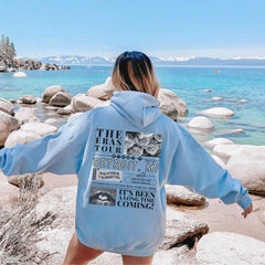 a woman in a blue hoodie standing on a beach
