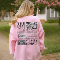 a woman in a pink sweatshirt is standing on a sidewalk