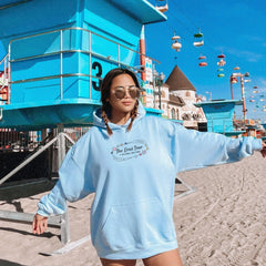 a woman in a blue hoodie standing on the beach