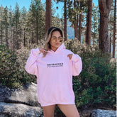 a woman in a pink hoodie posing for a picture