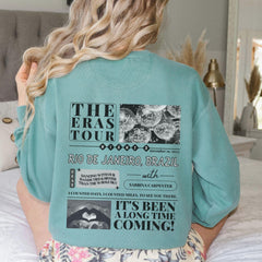 a woman sitting on top of a bed wearing a blue shirt