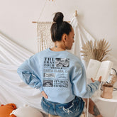 a woman sitting on a stool reading a book