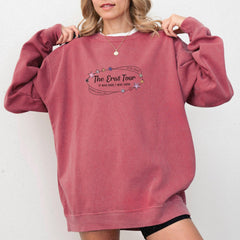 a woman wearing a pink sweatshirt with the words the great tour on it