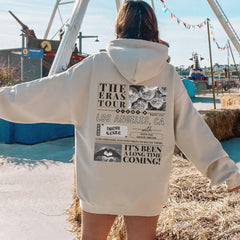 a woman in a white hoodie standing in front of a ferris wheel