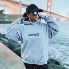 a woman in a gray hoodie is standing near the water