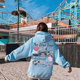 a woman in a blue hoodie is walking towards a roller coaster