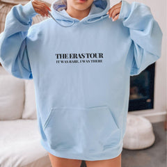 a woman wearing a blue sweatshirt with the words the eras tour on it