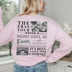 a woman in a pink sweatshirt is looking out a window