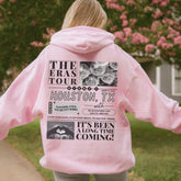 a woman in a pink hoodie is walking down a sidewalk
