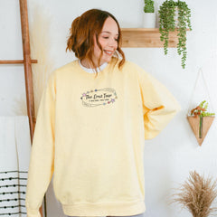 a woman wearing a yellow sweatshirt with the words the love four printed on it