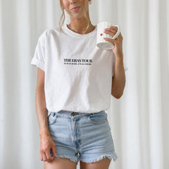 a woman in a white shirt is holding a cup