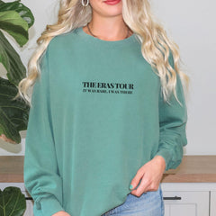 a woman wearing a green sweatshirt with the words the eras tour on it