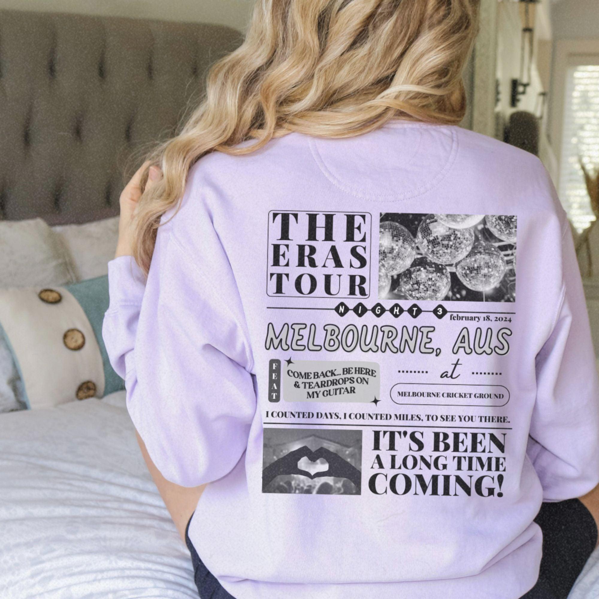 a woman sitting on top of a bed wearing a purple shirt