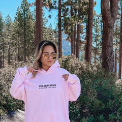 a woman wearing a pink hoodie and sunglasses