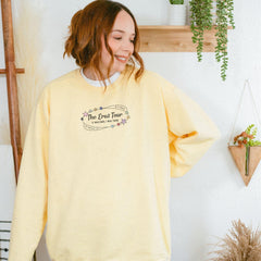 a woman standing in front of a wall wearing a yellow sweatshirt