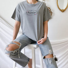 a woman sitting on a stool wearing ripped jeans