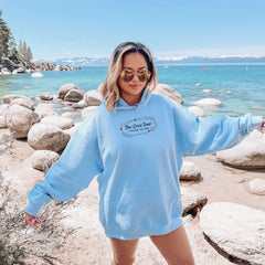 a woman in a blue hoodie standing on a beach