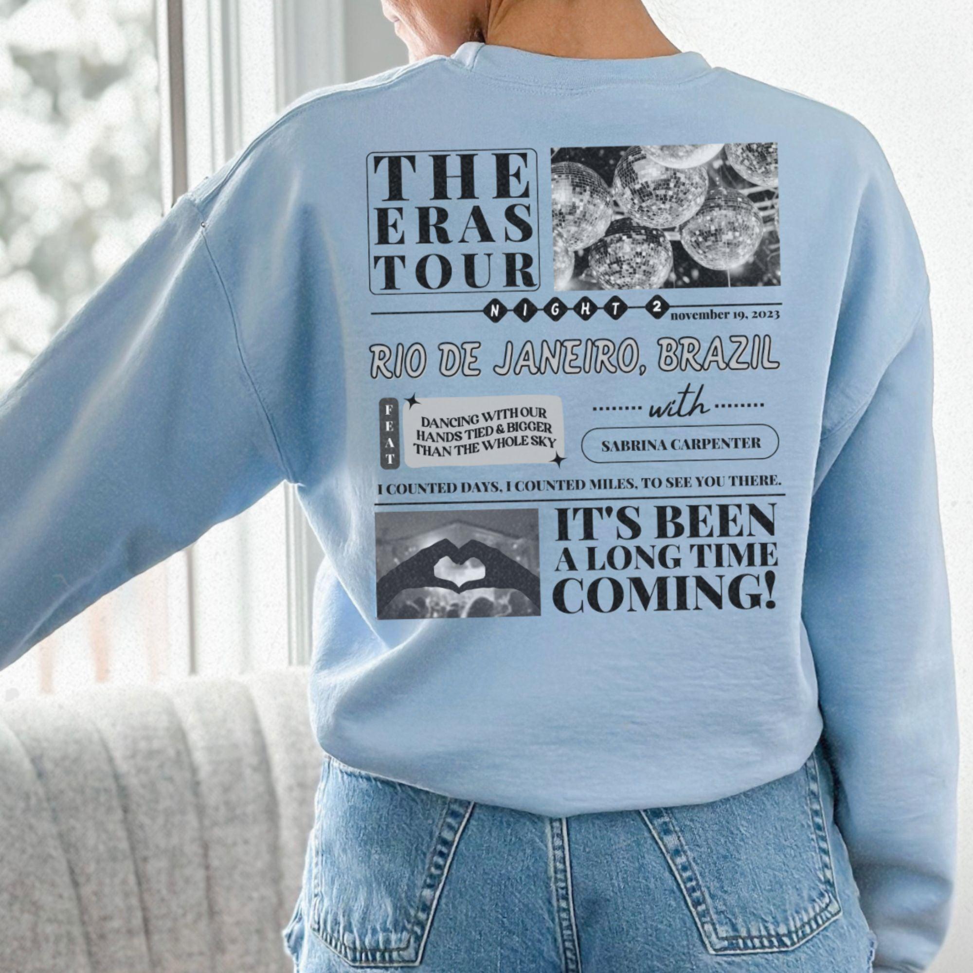 a woman wearing a blue sweatshirt with the words the eras tour on it