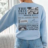 a woman wearing a blue sweatshirt with the words the eras tour on it
